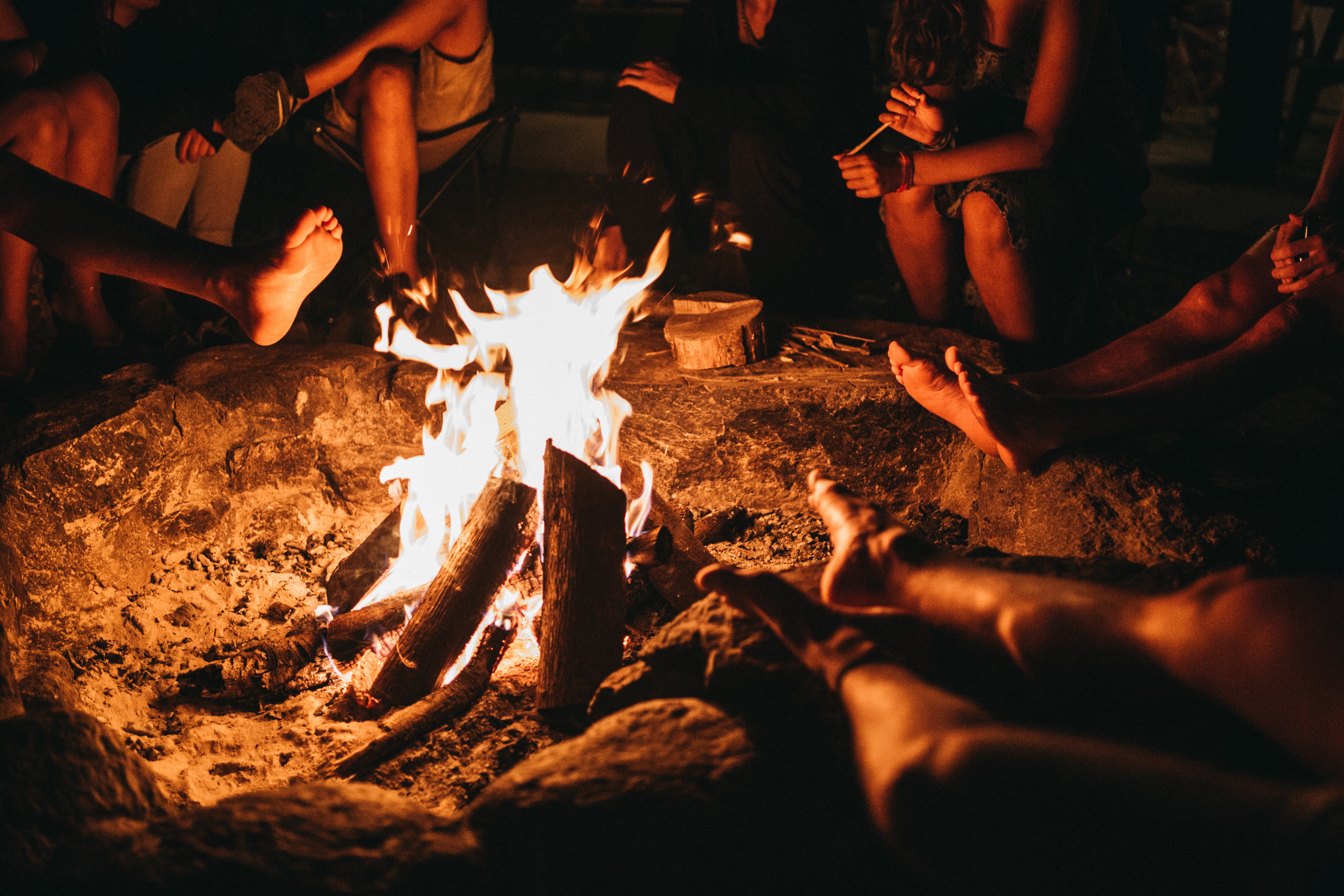 people sitting at a bonfire at night