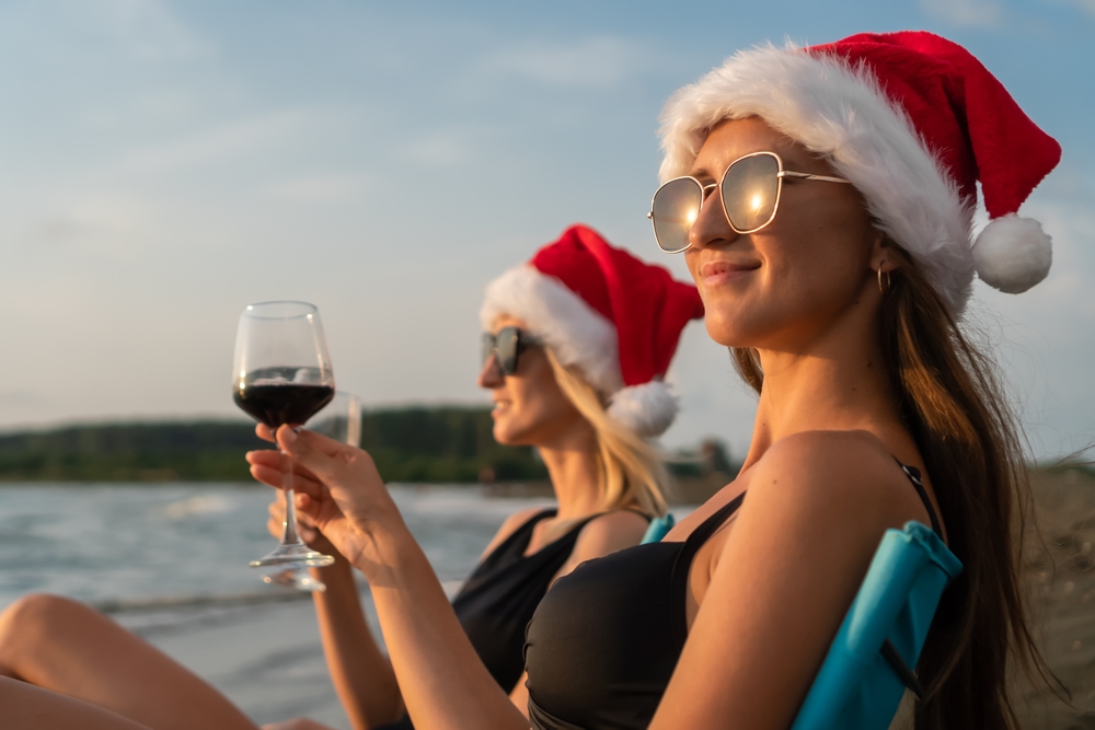 two women enjoying wine on the beach at christmas